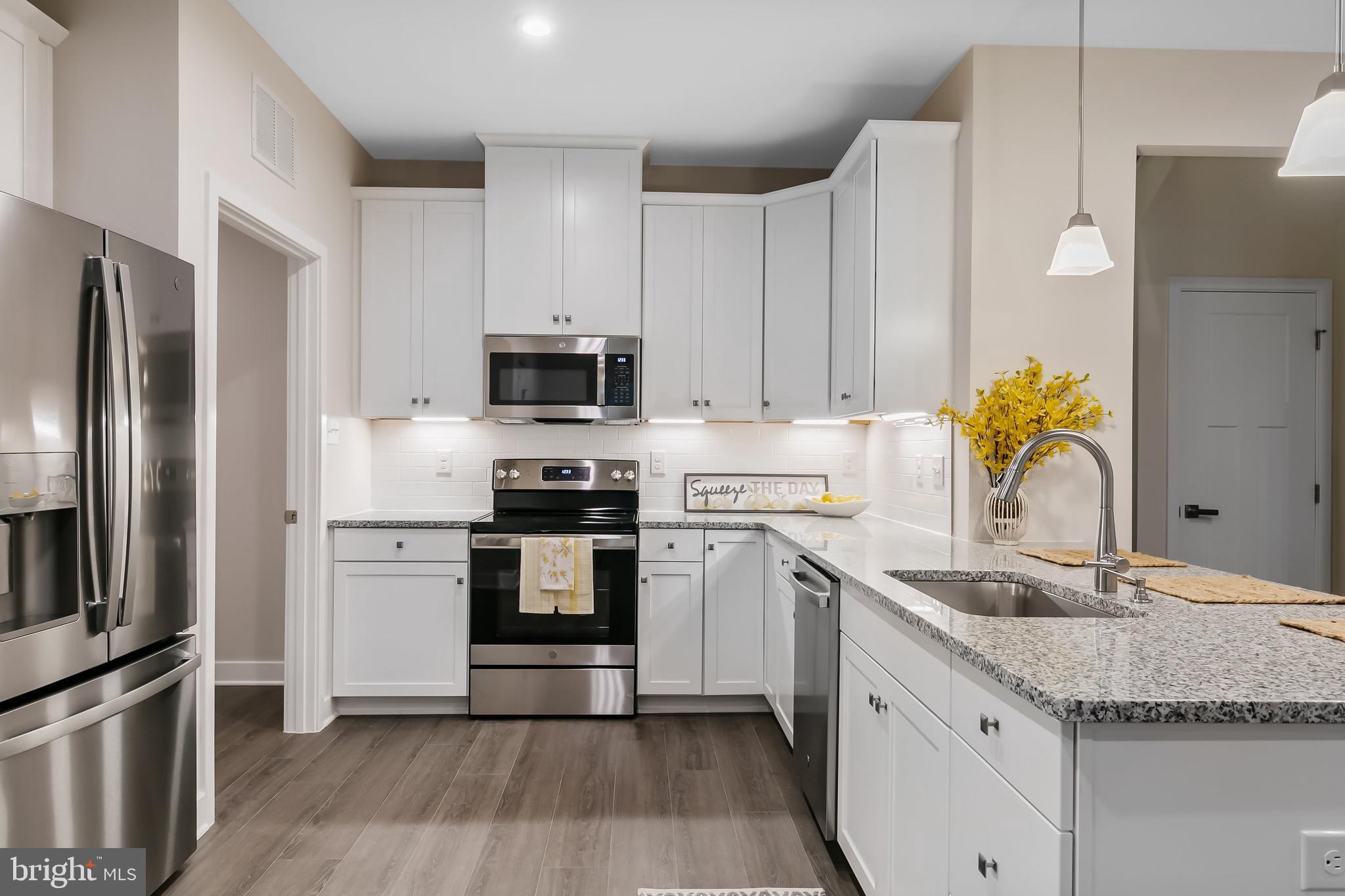 a kitchen with a sink a microwave a refrigerator and white cabinets