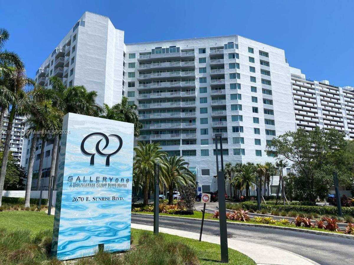 a view of a sign board with buildings in the background