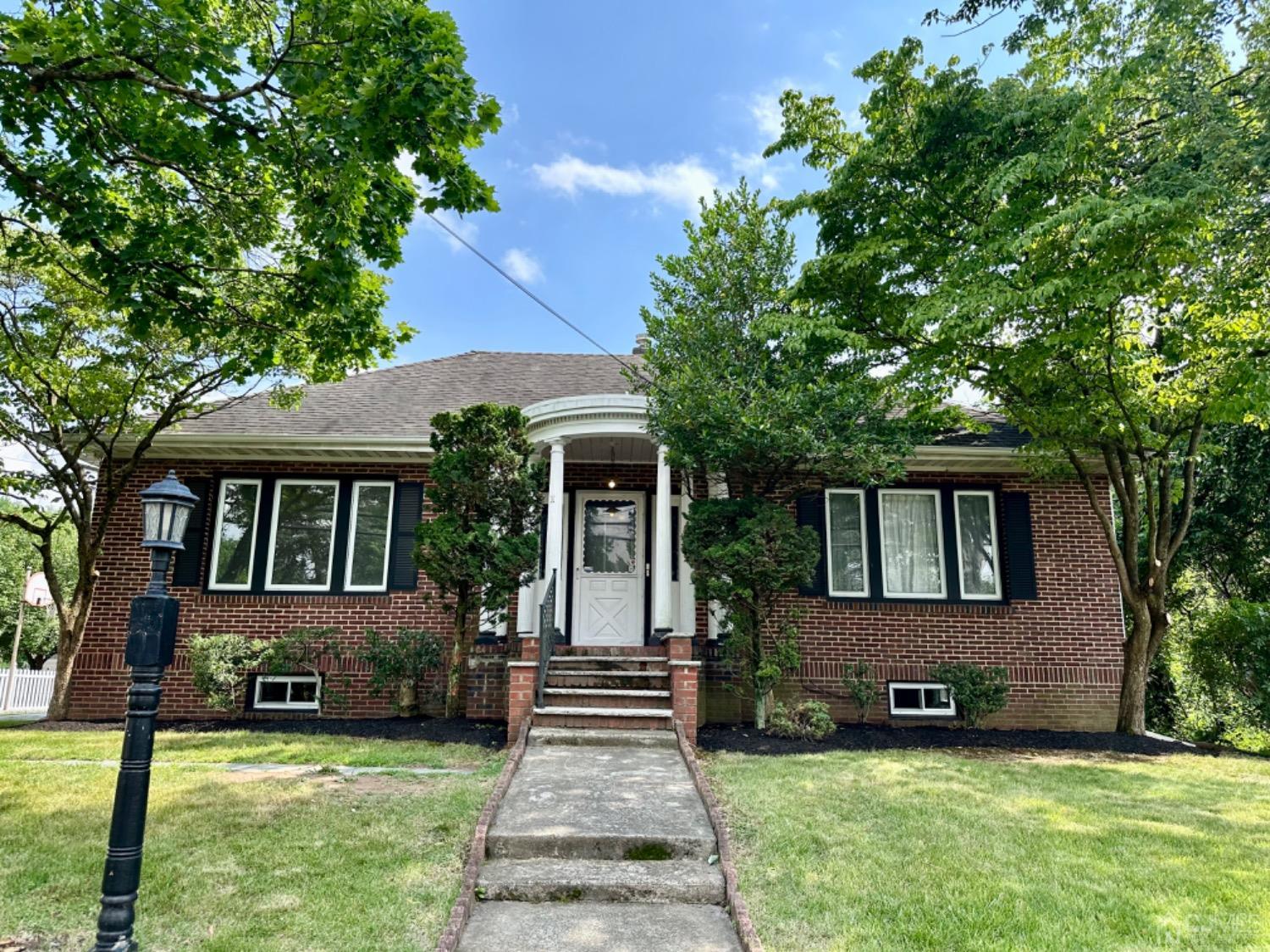 a front view of a house with a yard porch and a tree