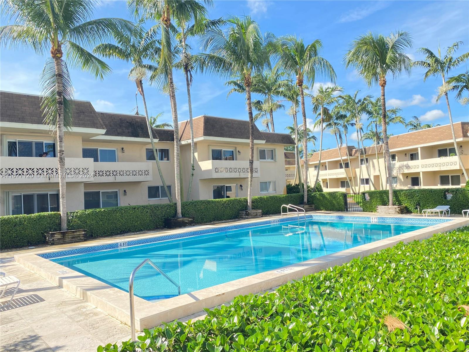 a view of a swimming pool with a yard and palm trees