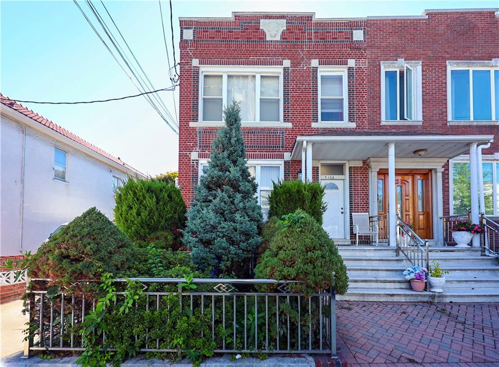 a view of a brick house with large windows and plants