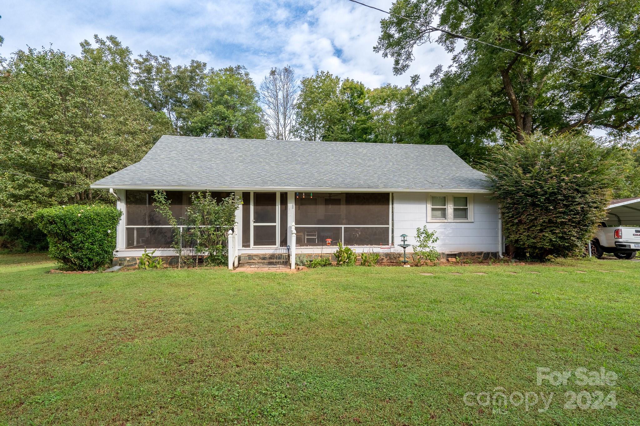 a front view of a house with a garden and trees