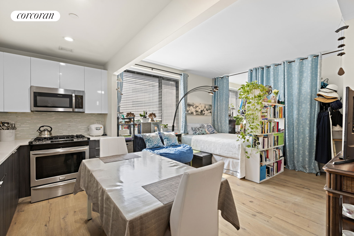 a living room with stainless steel appliances furniture a rug and a flat screen tv