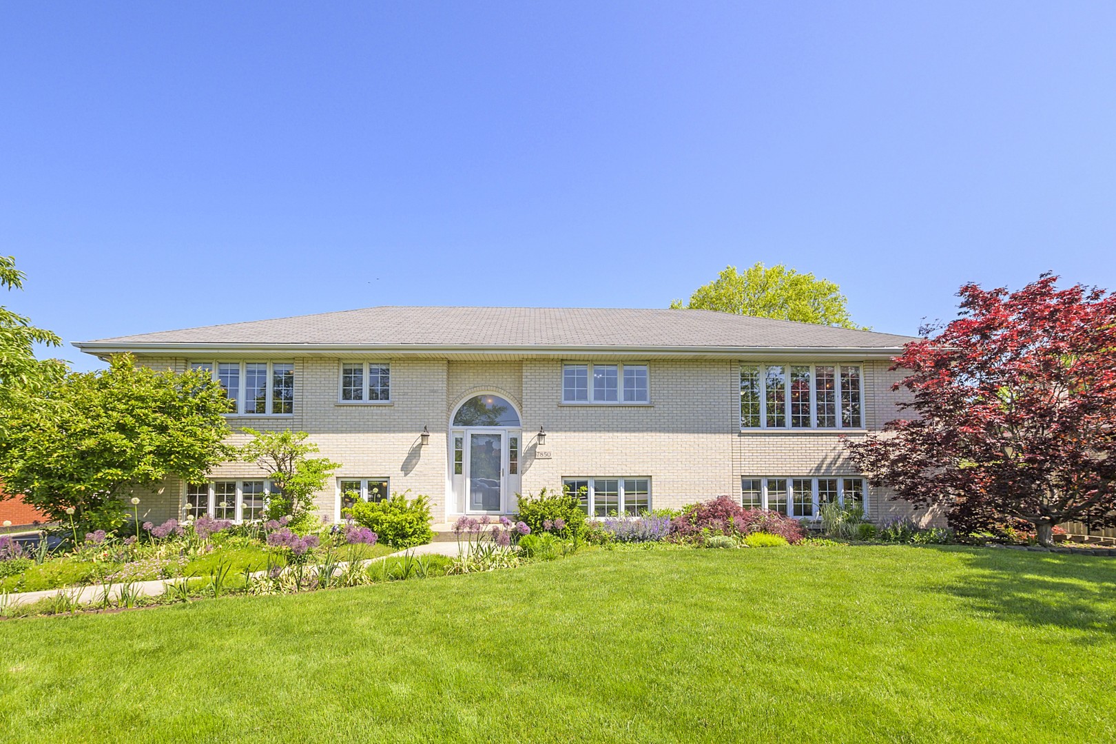 a front view of a house with a garden and plants