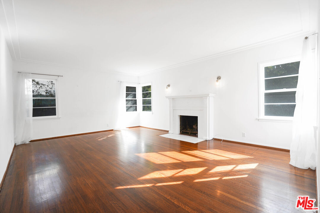 a view of empty room with wooden floor and fireplace