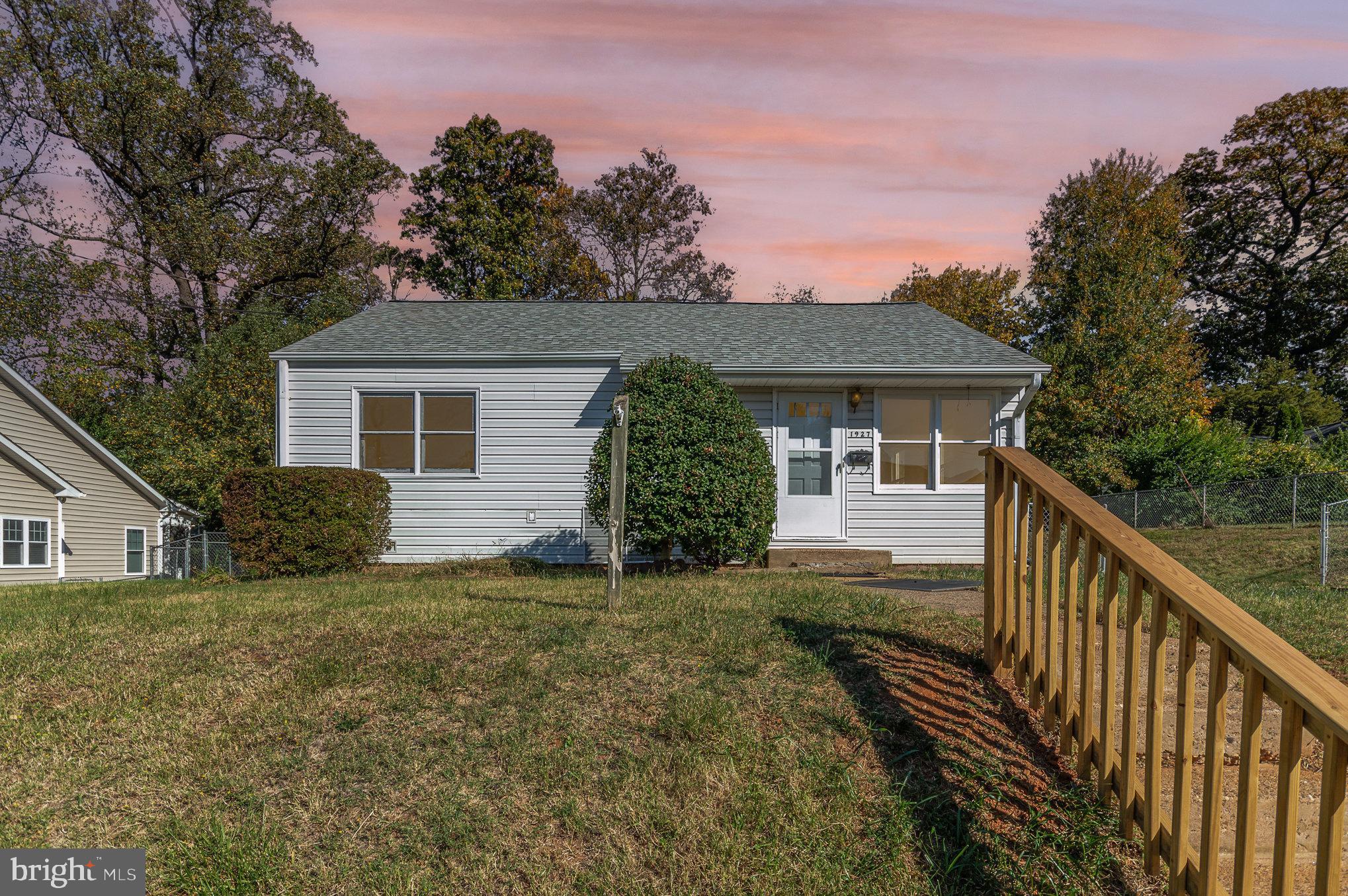 a front view of house with yard and trees in the background