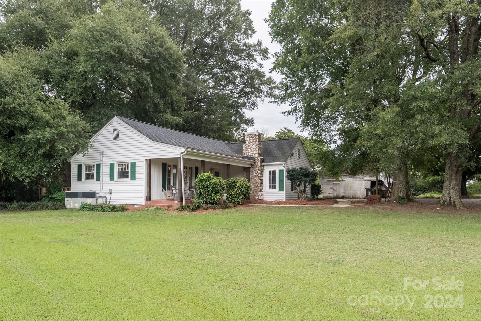 a front view of a house with a garden and trees