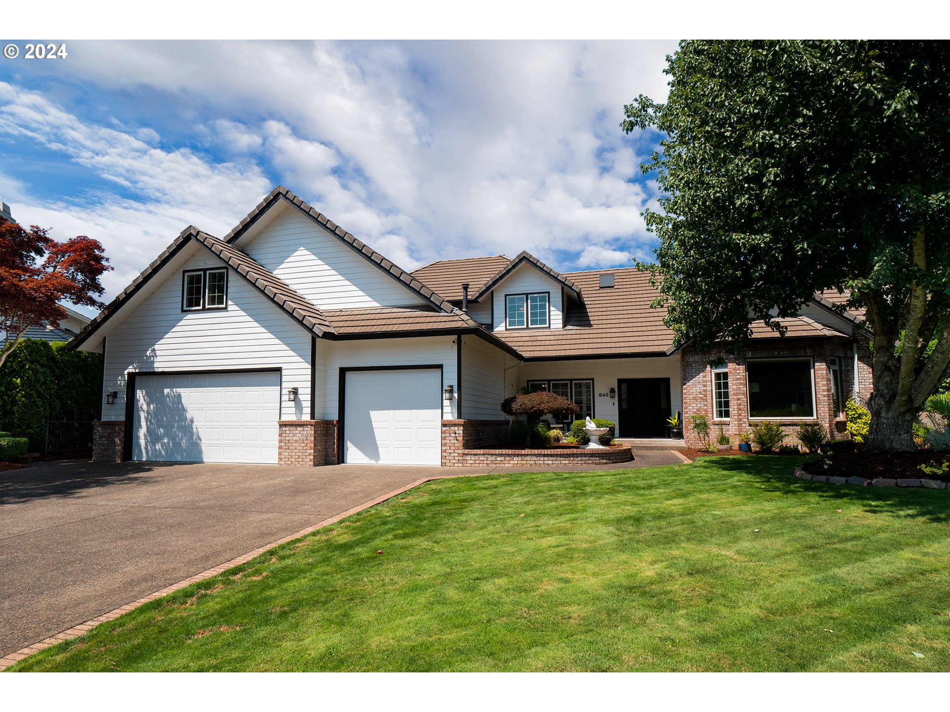 a front view of a house with a yard and trees