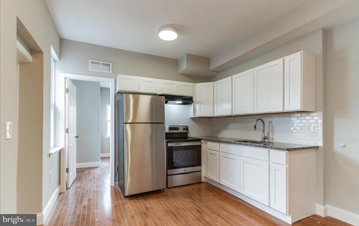 a kitchen with a refrigerator sink and cabinets