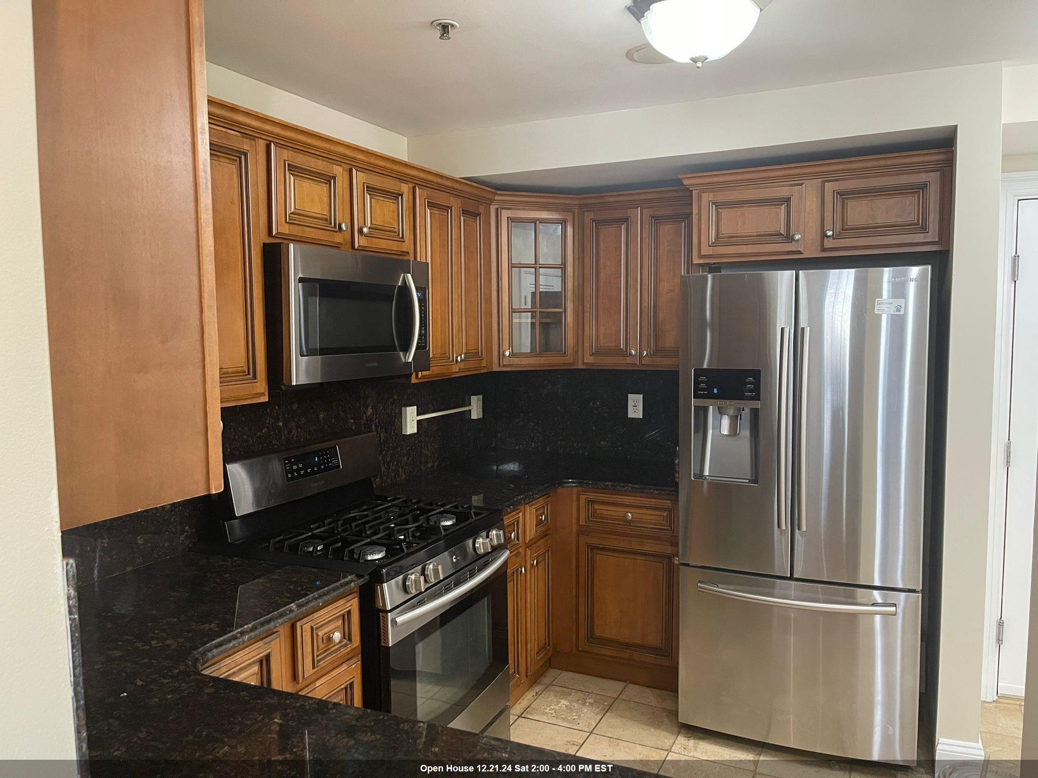 a kitchen with stainless steel appliances granite countertop a refrigerator and a stove top oven