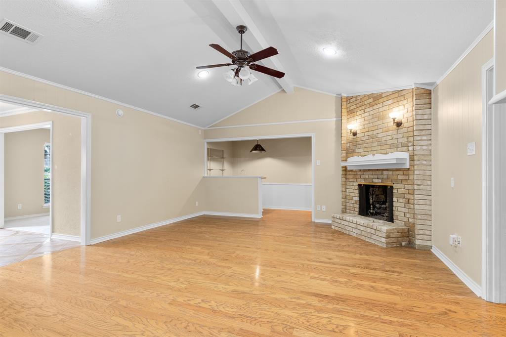 a view of a livingroom with a fireplace a ceiling fan and windows