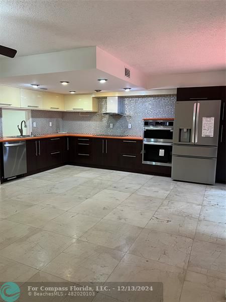 a large kitchen with granite countertop a refrigerator and a sink