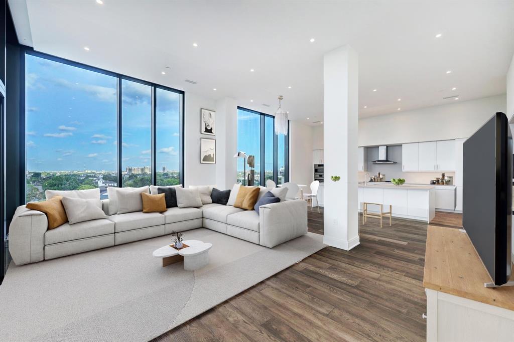 a living room with furniture large windows and wooden floor