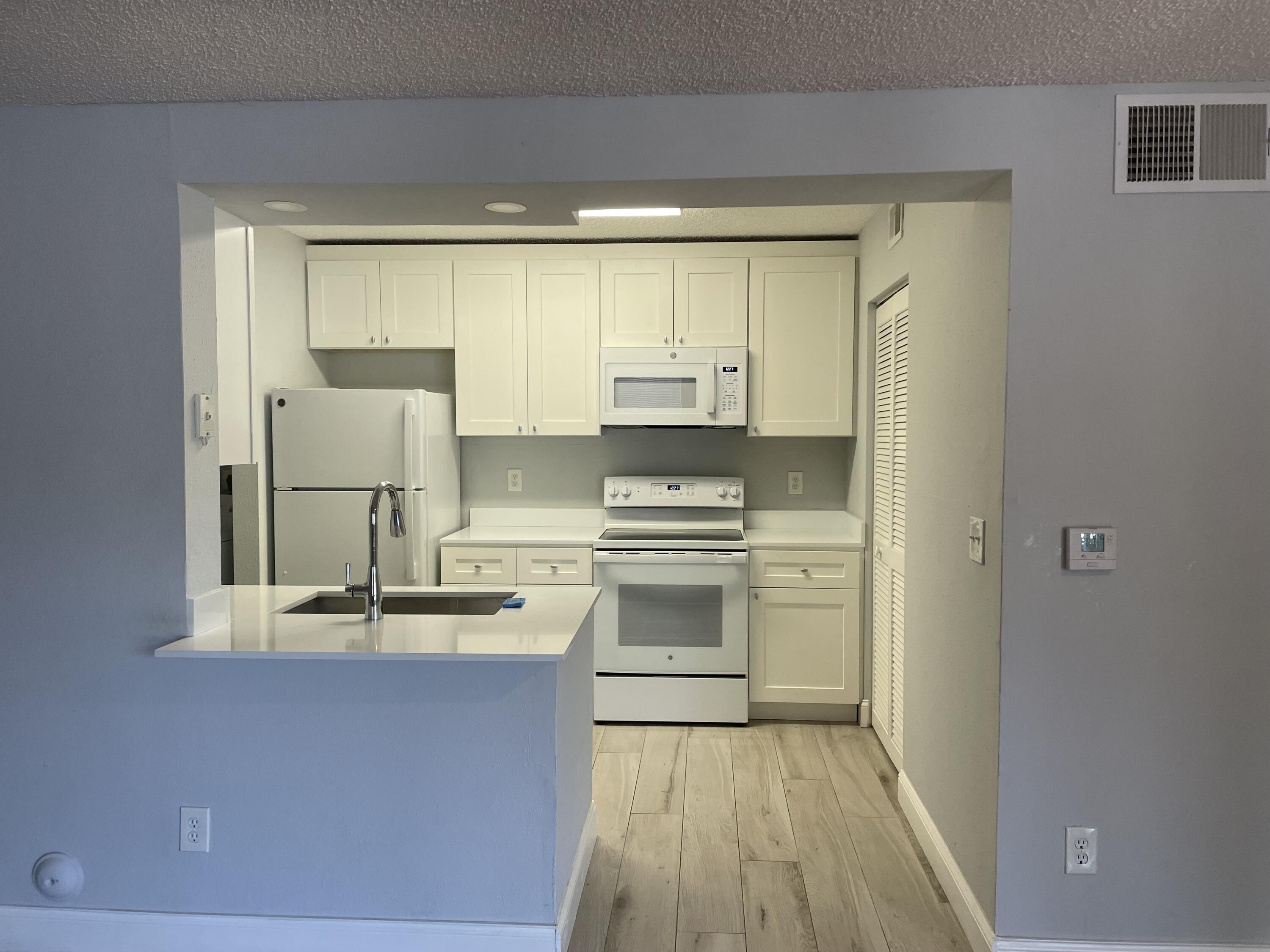 a kitchen with kitchen island white cabinets and refrigerator