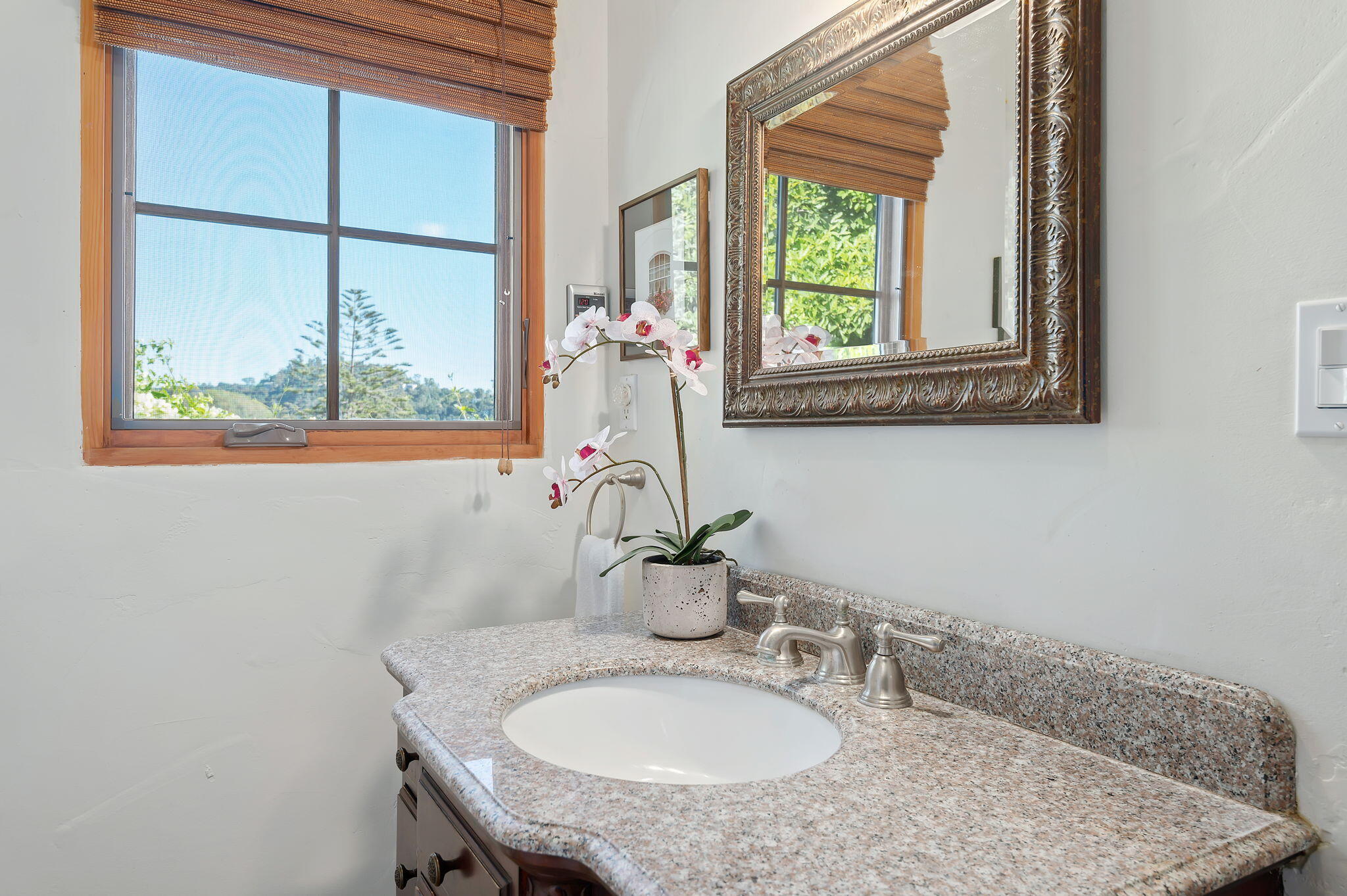 a bathroom with a granite countertop sink and a window