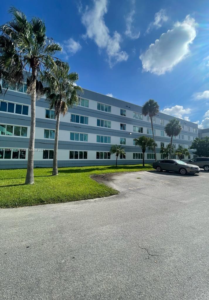 a view of a big building with a big yard and large trees