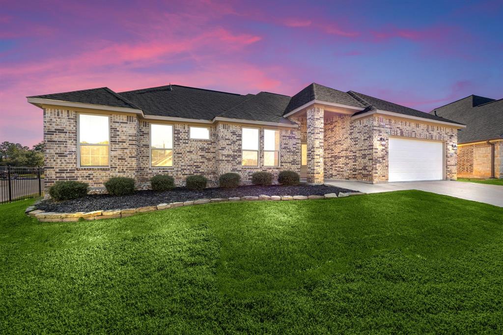 This is a single-story brick house with an attached two-car garage, well-manicured lawn, and landscaping. 