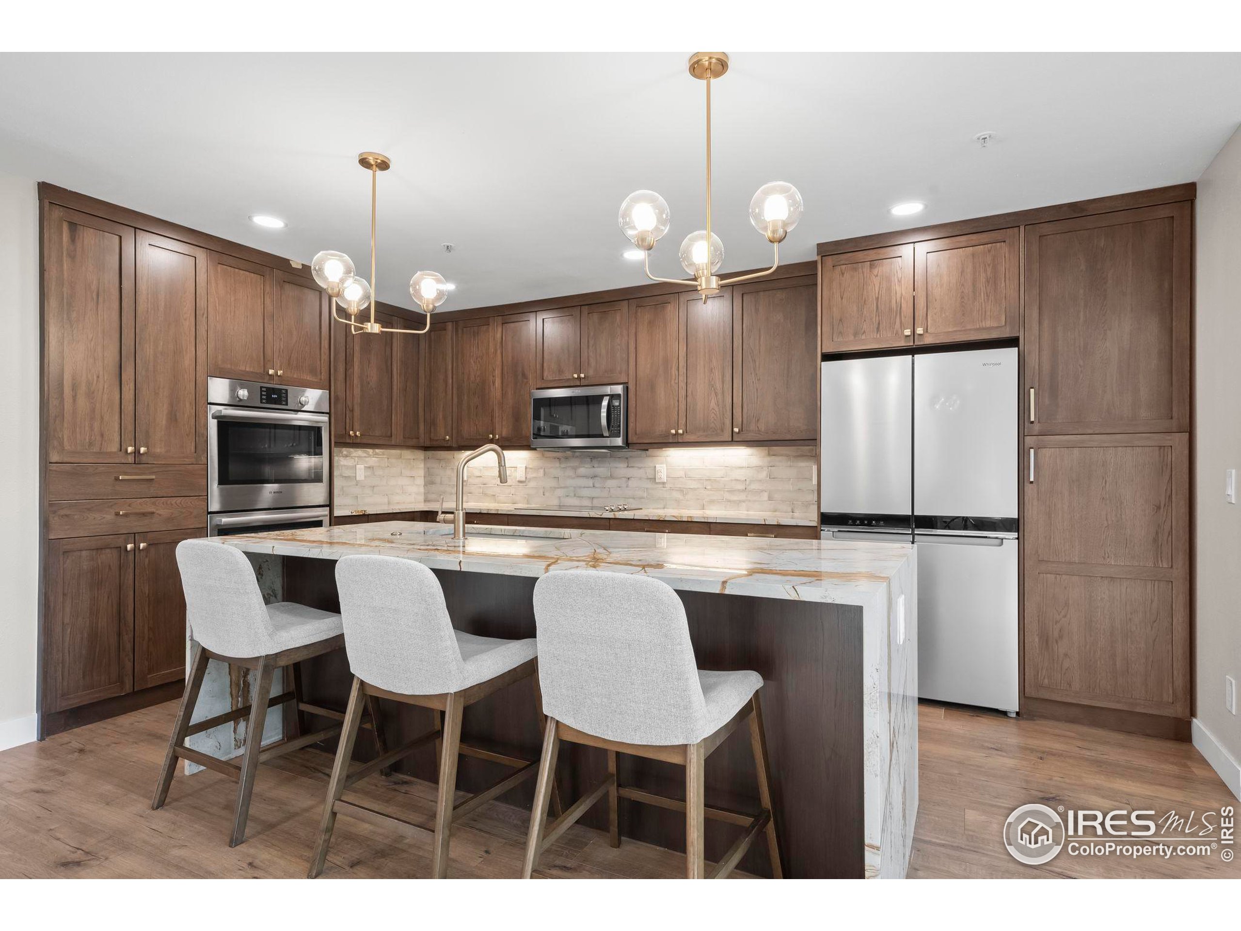 a kitchen with kitchen island granite countertop a table chairs refrigerator and microwave