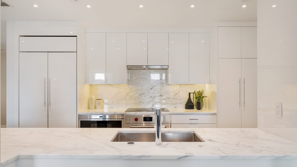 a kitchen with stainless steel appliances kitchen island granite countertop white cabinets and sink