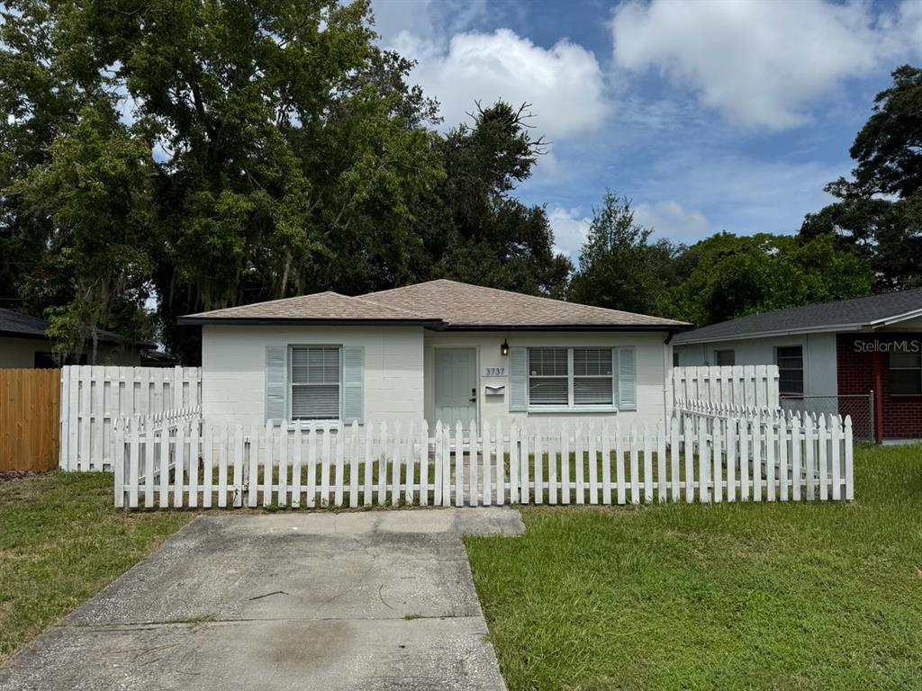 a view of a wooden house with a small yard and wooden fence