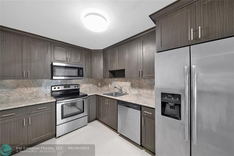 a kitchen with stainless steel appliances granite countertop a refrigerator and a stove top oven