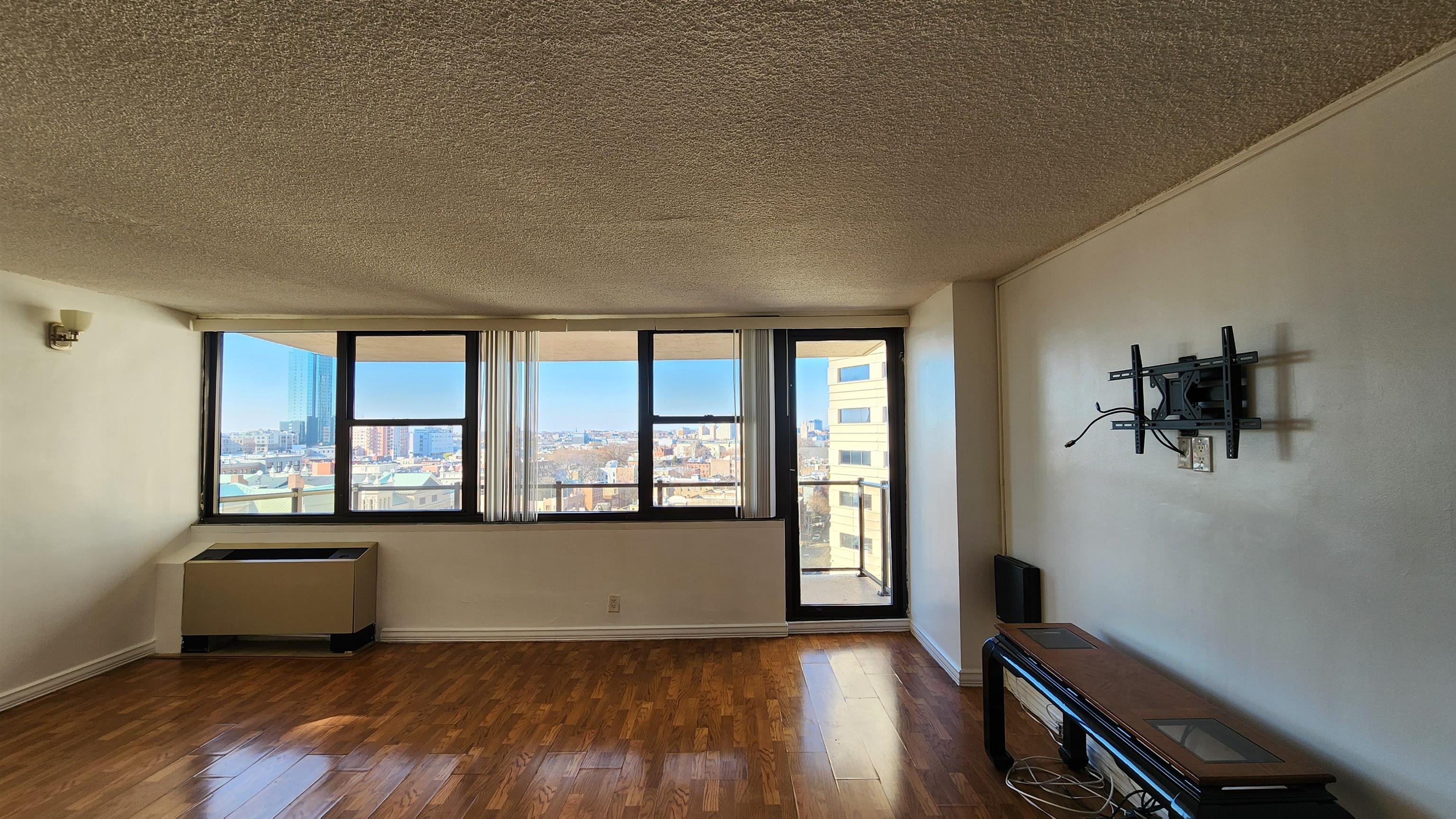 an empty room with wooden floor and windows