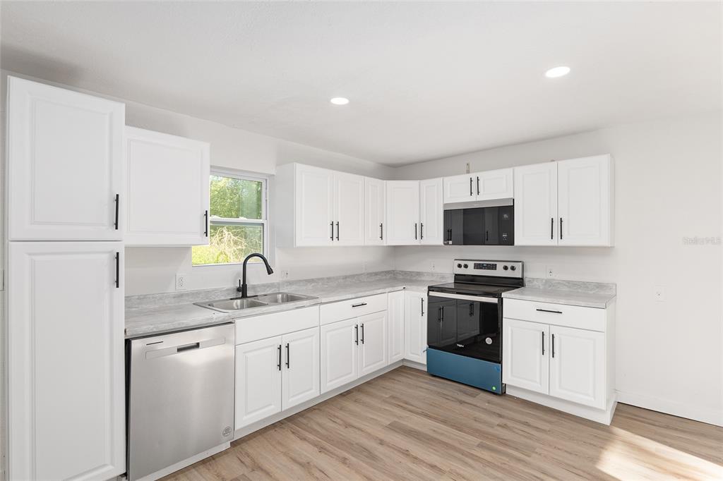 a kitchen with stainless steel appliances granite countertop a sink a stove and cabinets