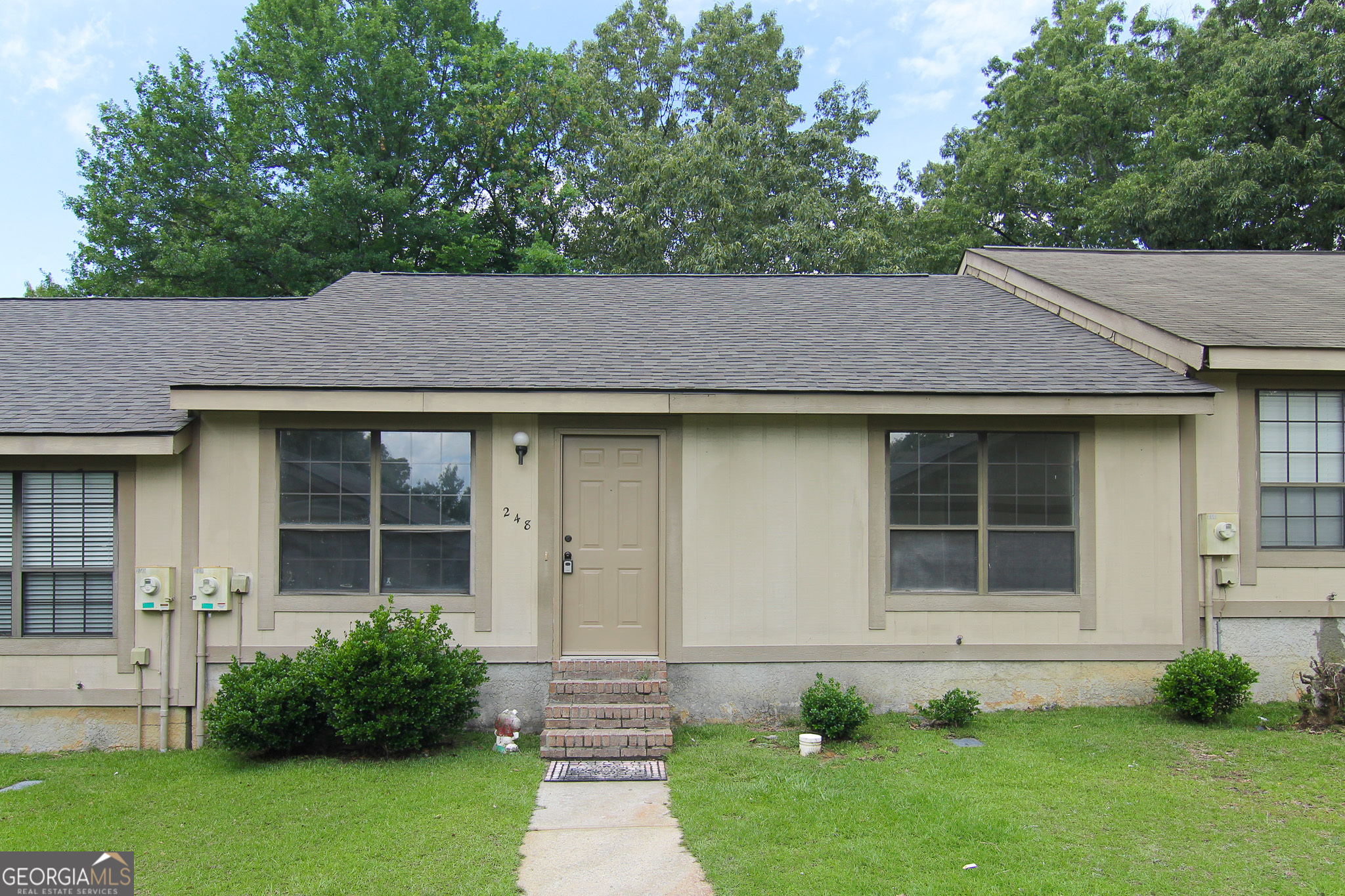 a front view of a house with a garden and plants