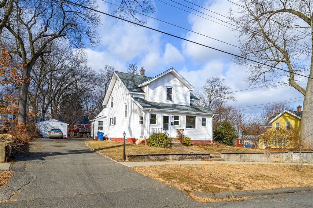 a view of a white house with a large tree and a small yard