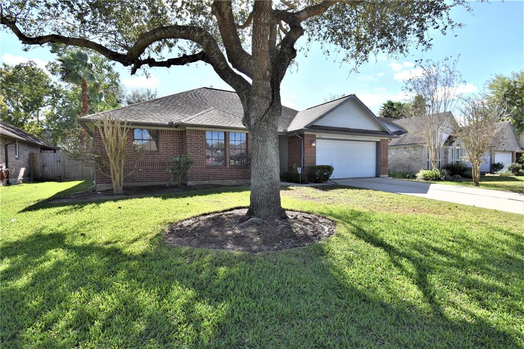 a front view of a house with a yard and large tree