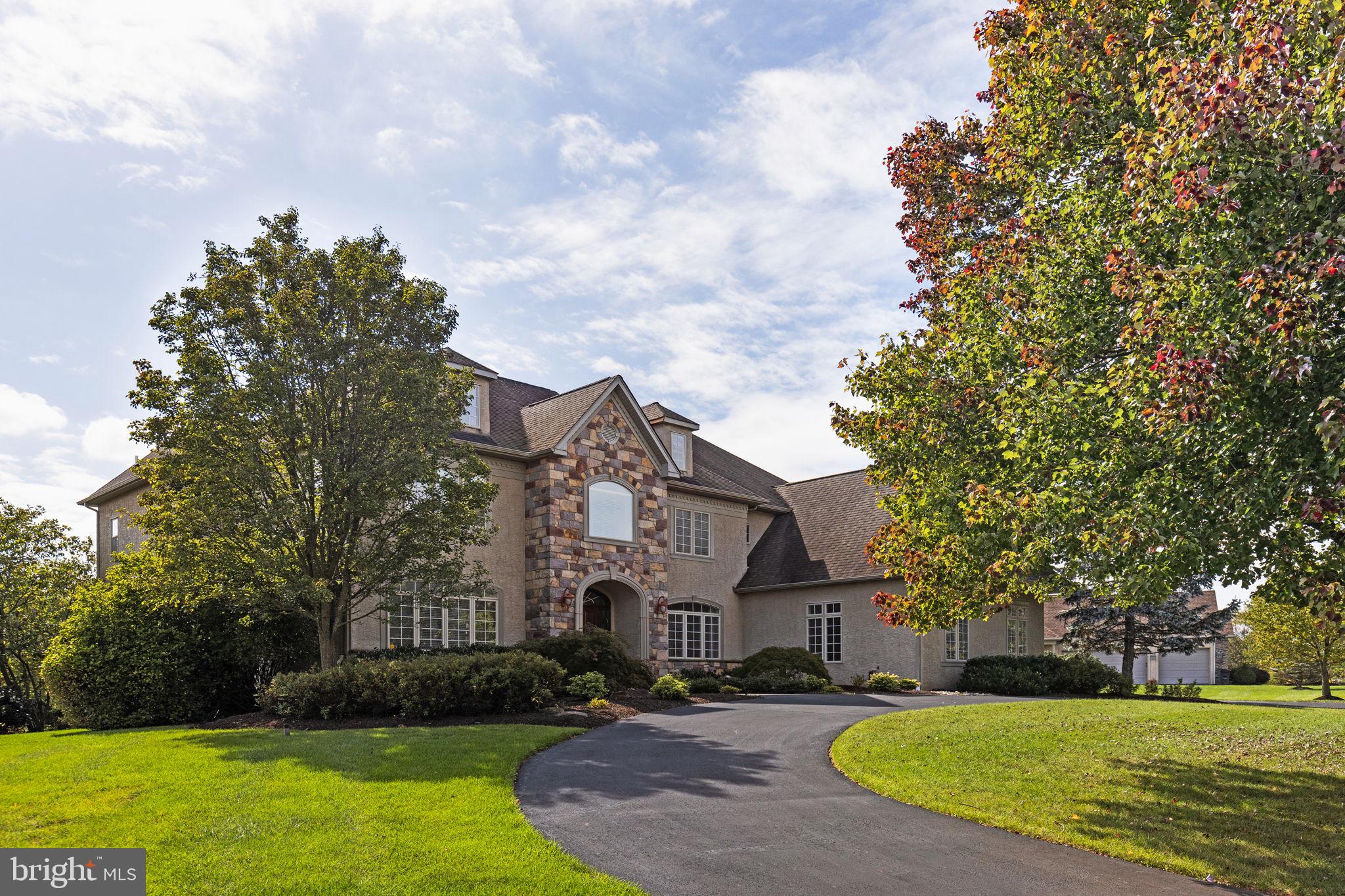 a view of a white house next to a yard with big trees