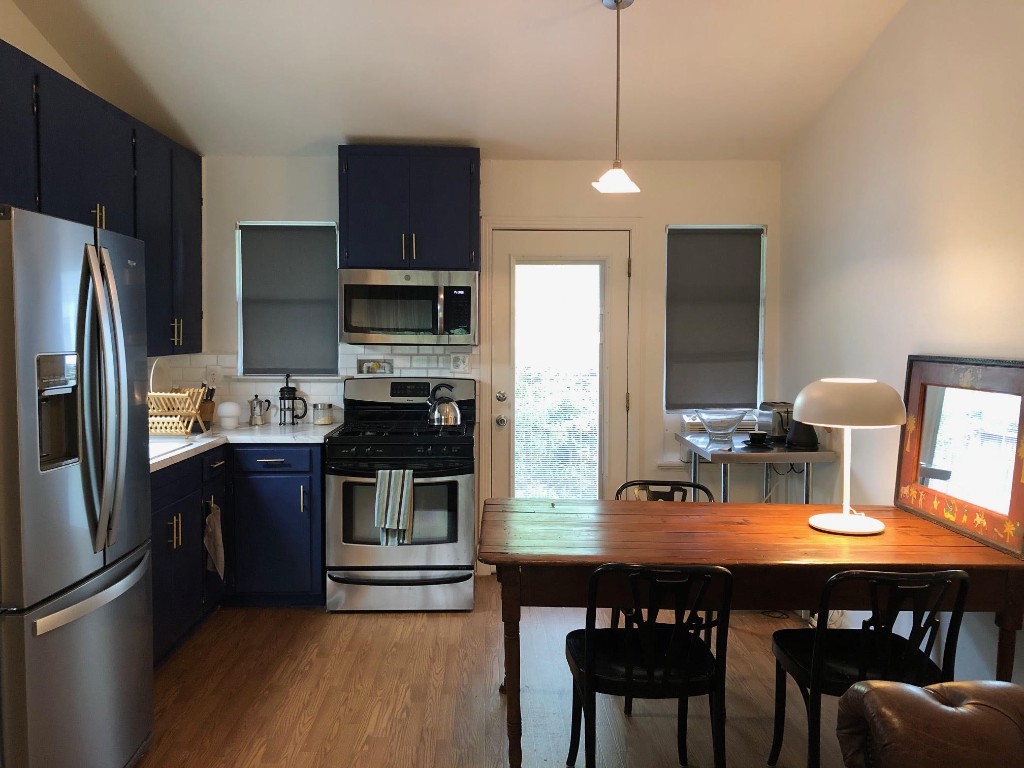 a kitchen with stainless steel appliances a stove a refrigerator and a dining table