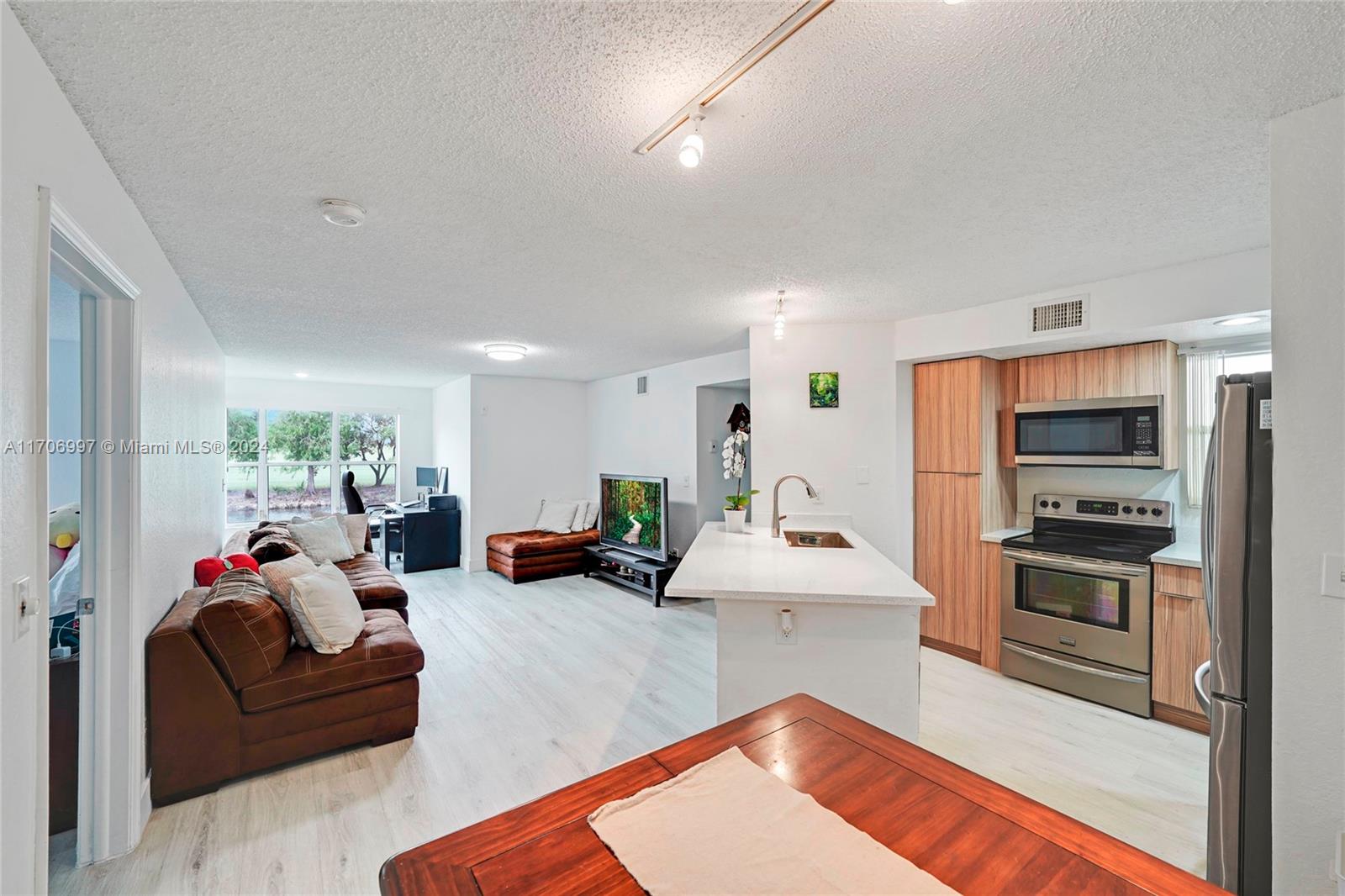 a living room with furniture kitchen area and a wooden floor