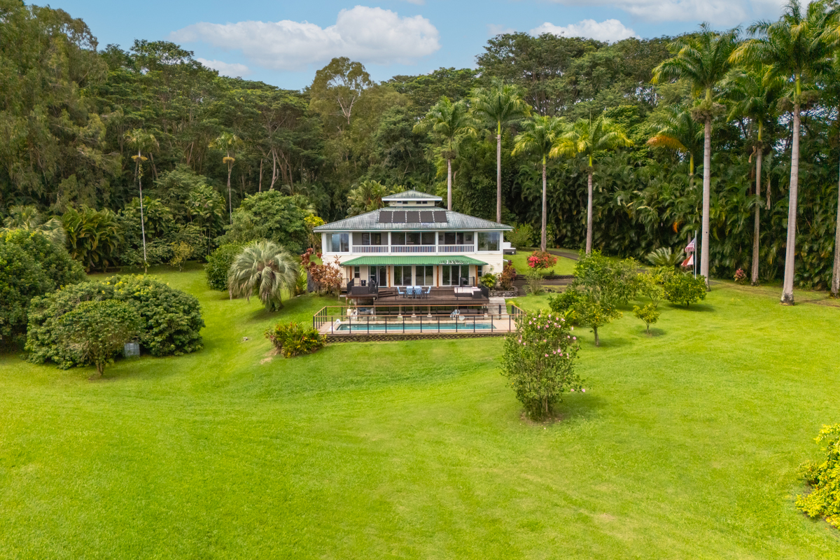 a view of a house with a big yard and large trees