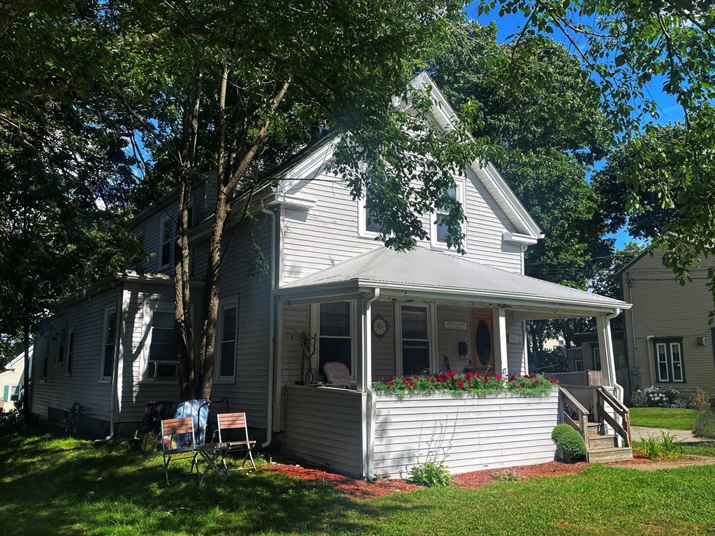 a view of a house with a yard and large tree