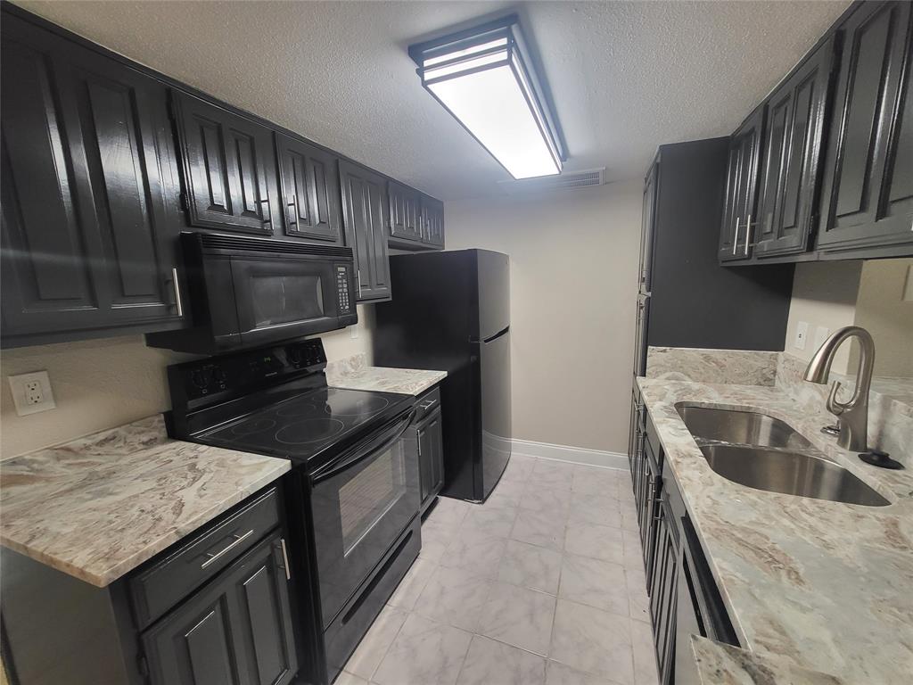 a kitchen with granite countertop stainless steel appliances a sink stove and refrigerator