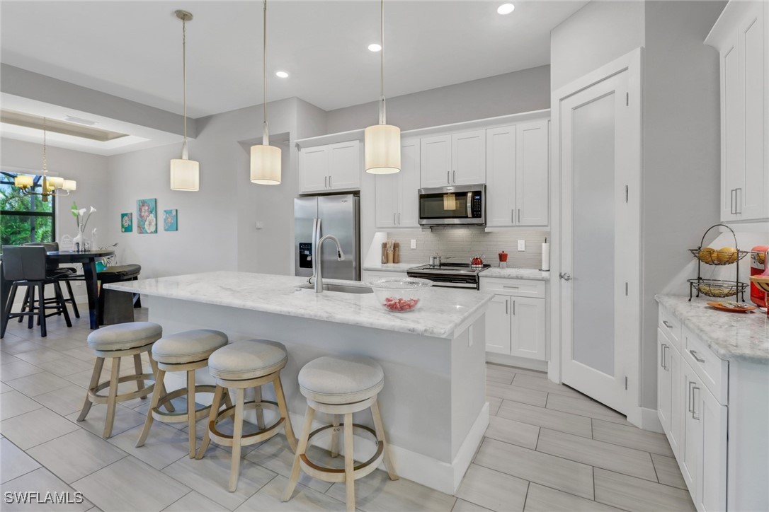 a kitchen with stainless steel appliances a dining table chairs sink and cabinets