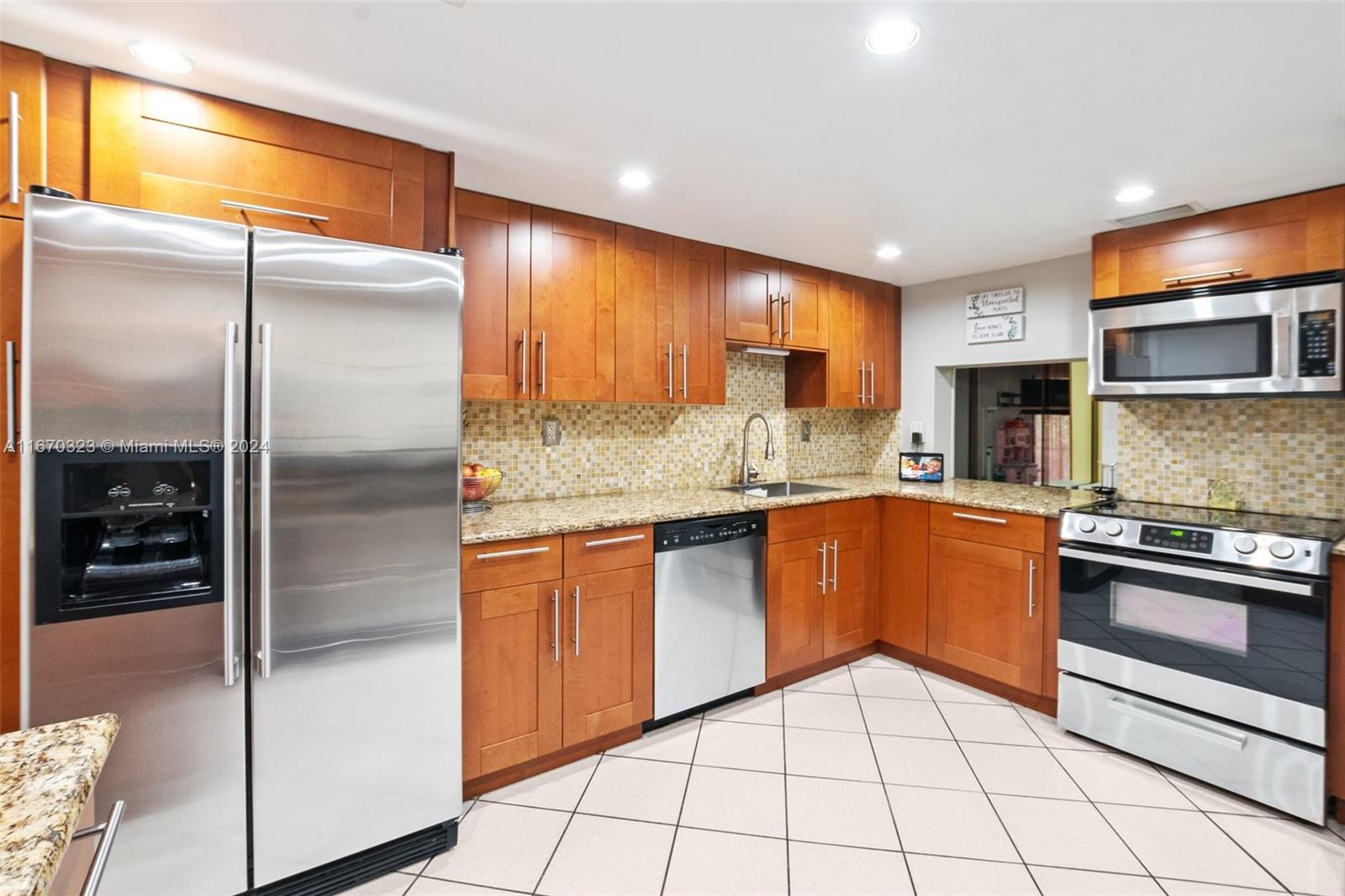 a kitchen with stainless steel appliances granite countertop a refrigerator a oven and a sink with granite countertops