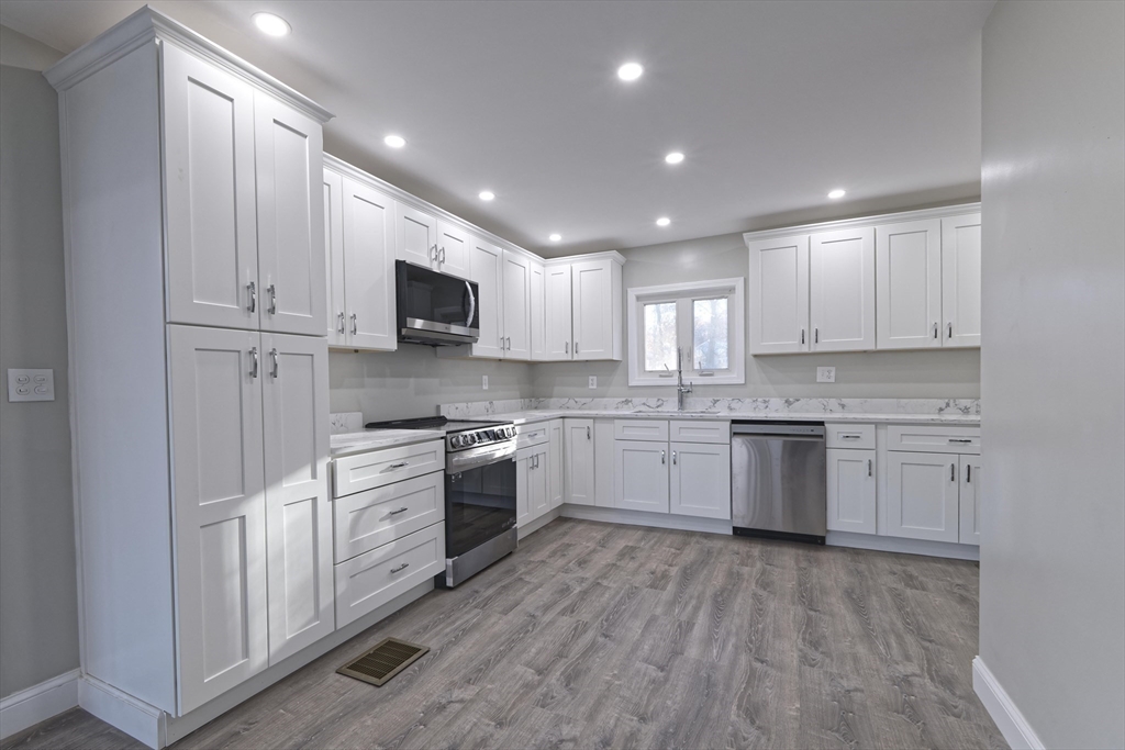 a kitchen with granite countertop white cabinets and stainless steel appliances