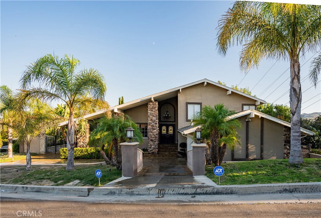 a view of a house with a yard and palm trees