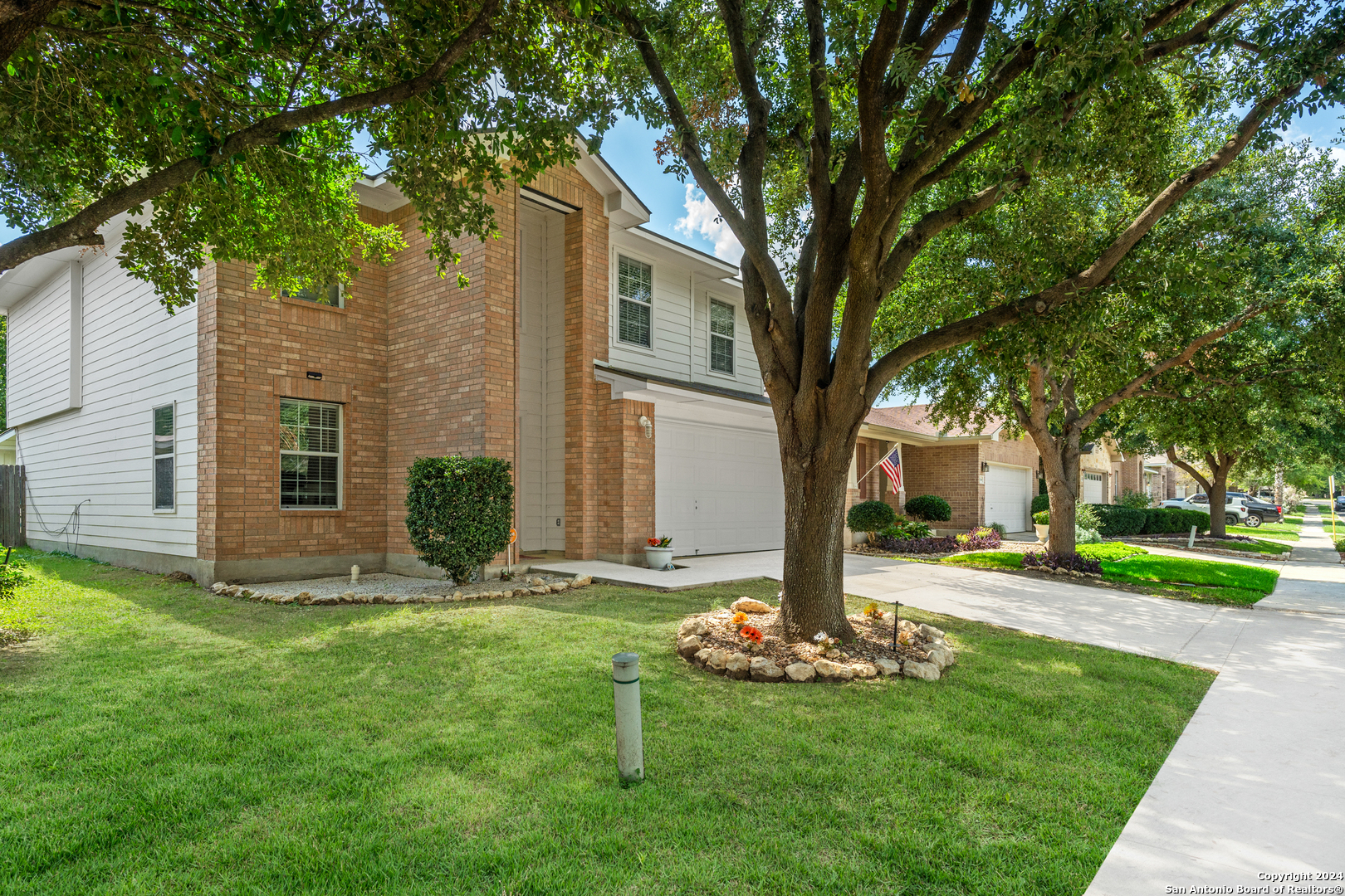 a front view of a house with garden and trees