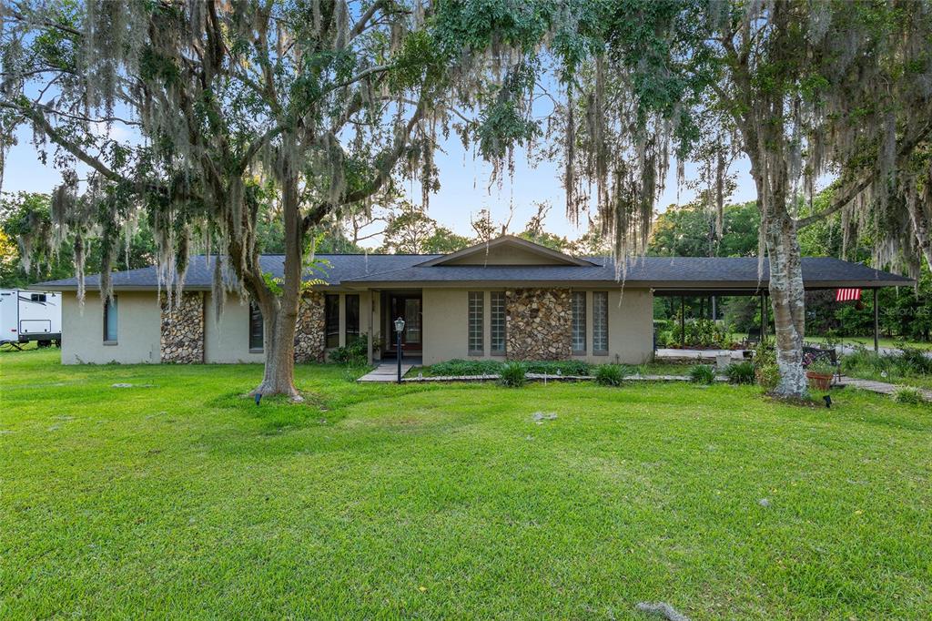 a view of a brick house with a big yard and large trees