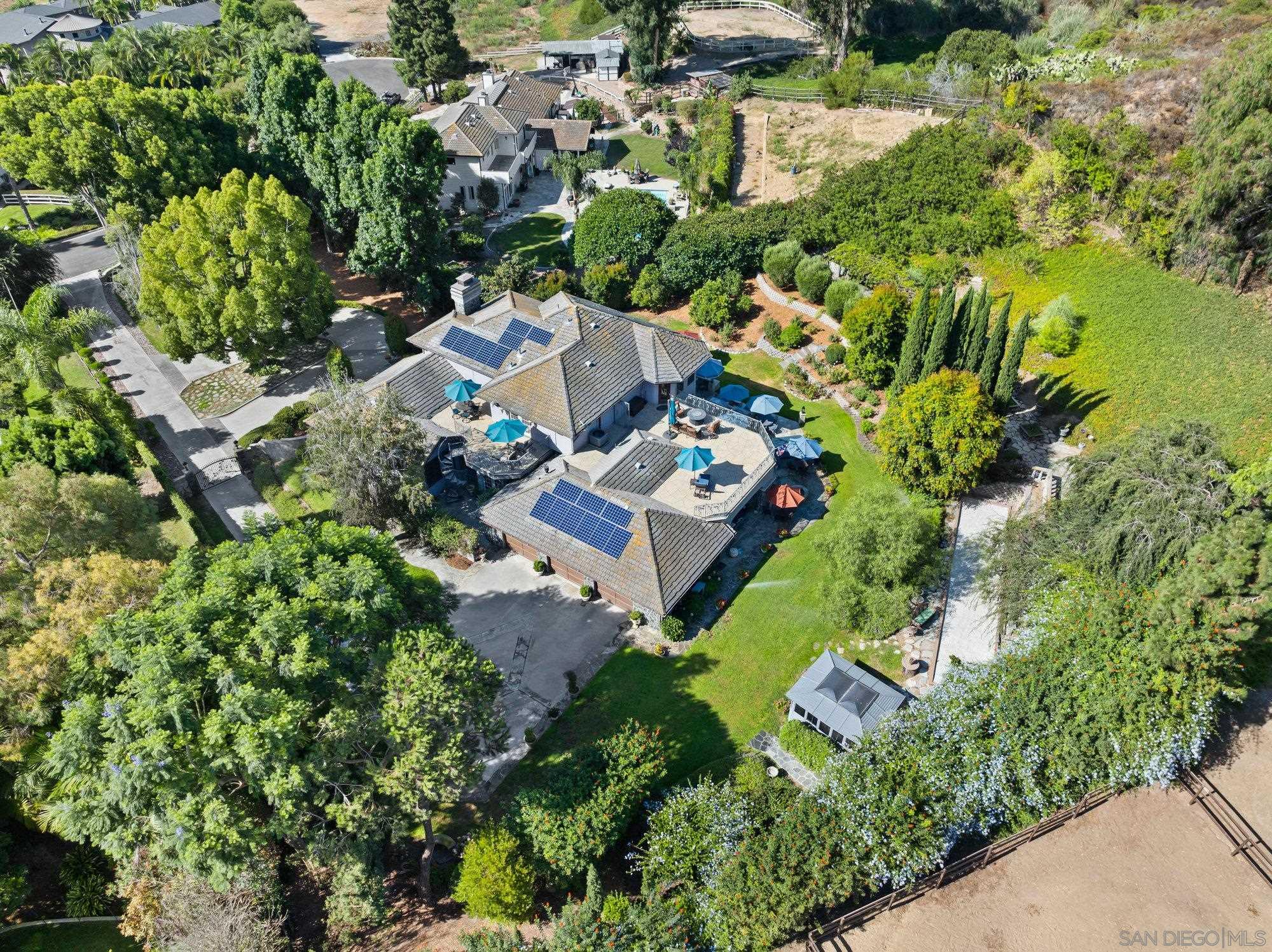 an aerial view of residential house with outdoor space and trees all around