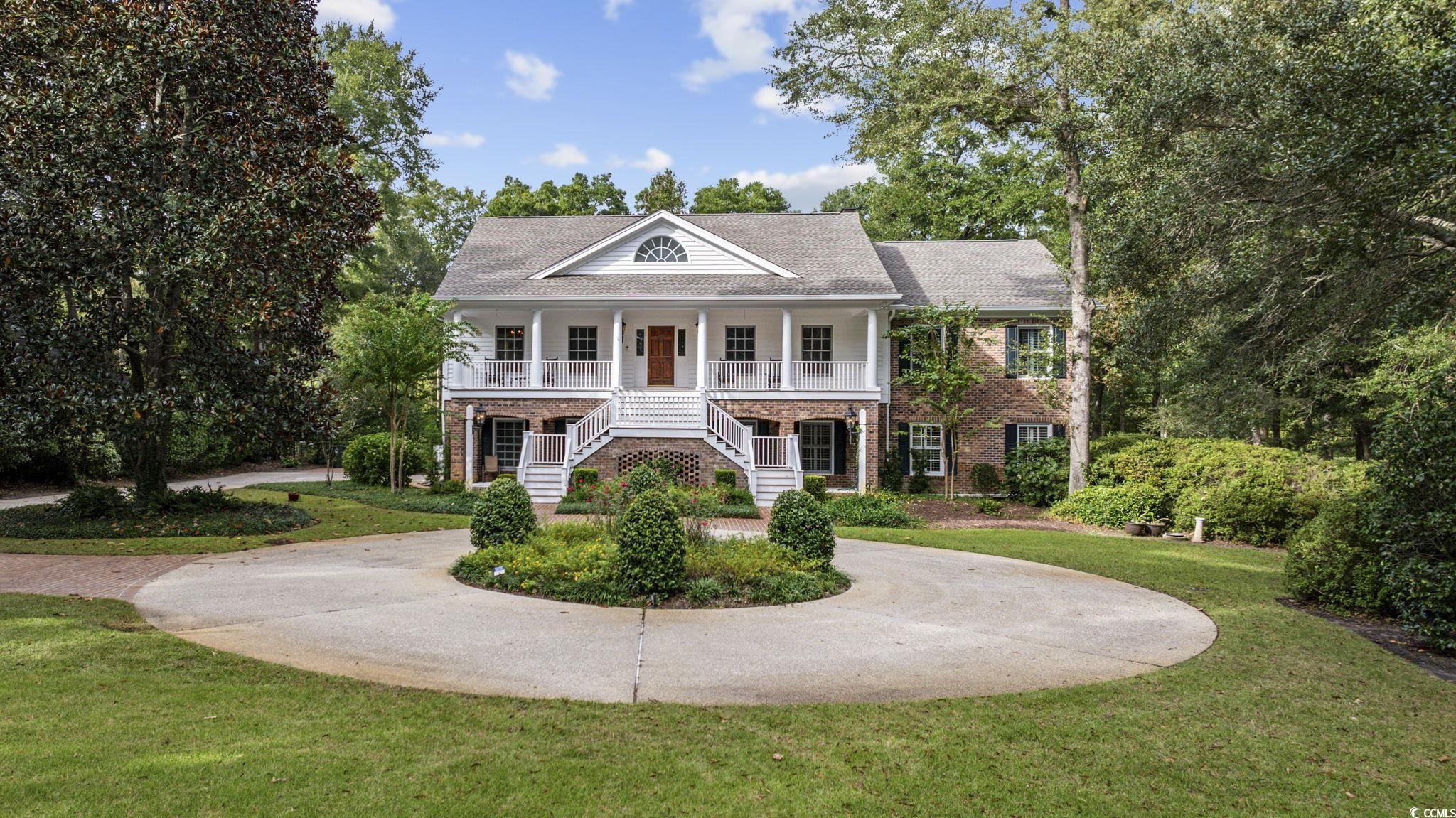 Greek revival house featuring a front lawn and cov