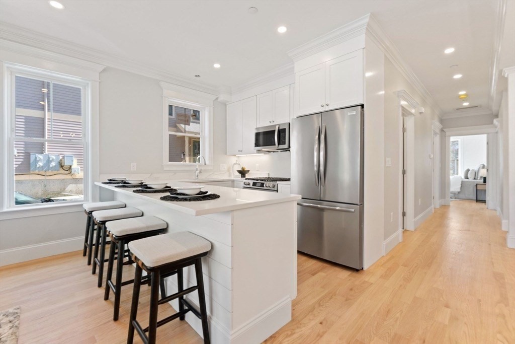 a kitchen with refrigerator a stove and a dining table with wooden floor