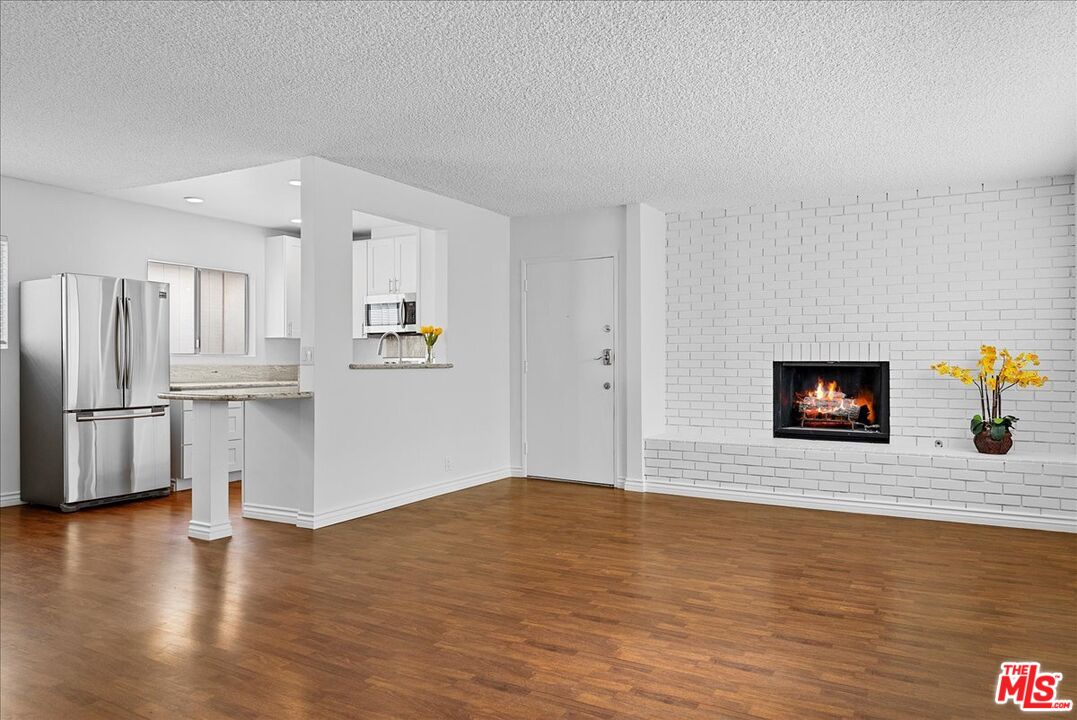 a view of a kitchen with wooden floor and electronic appliances