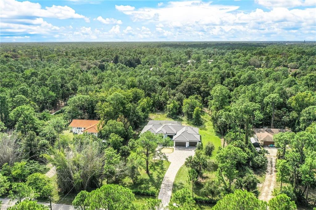 an aerial view of residential houses with outdoor space and trees