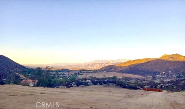 a view of a dry field with mountains in the background