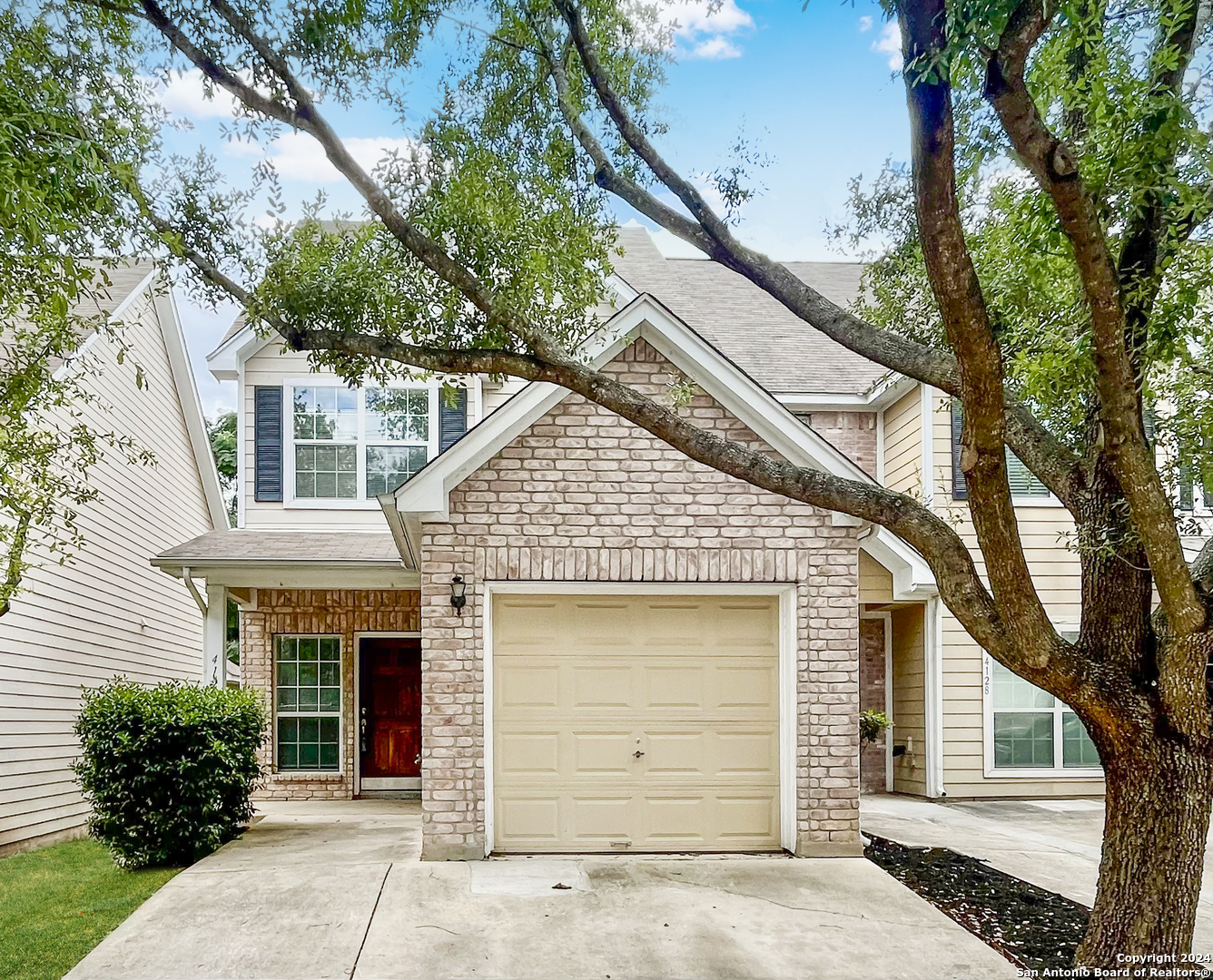 a front view of a house with a tree