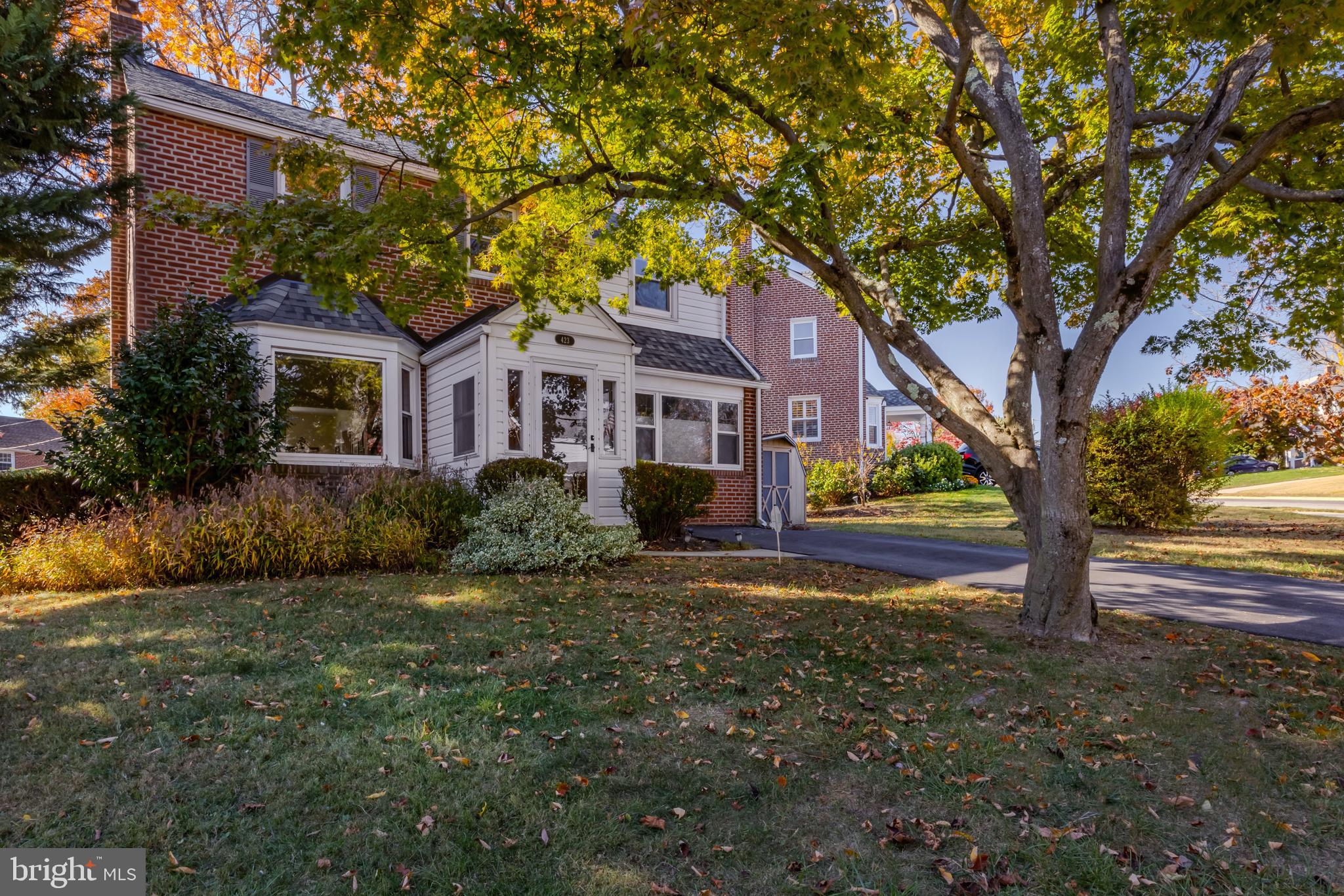 a front view of a house with garden and trees